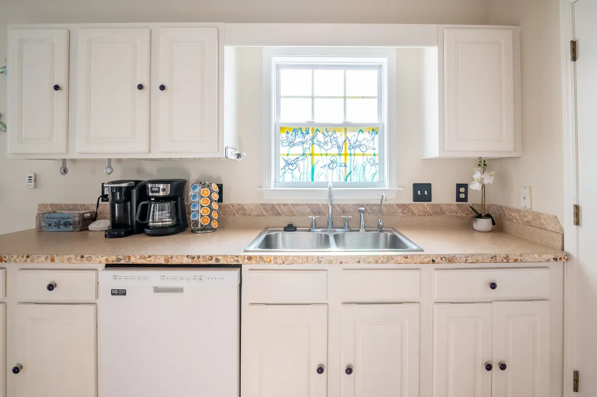 This welcoming kitchen scene centers on a stained glass window, countertop, coffee maker, and sink, capturing the warmth and simplicity of starting the day together. The setup invites guests to brew coffee, share easy breakfasts, and prepare for a day of local exploration.