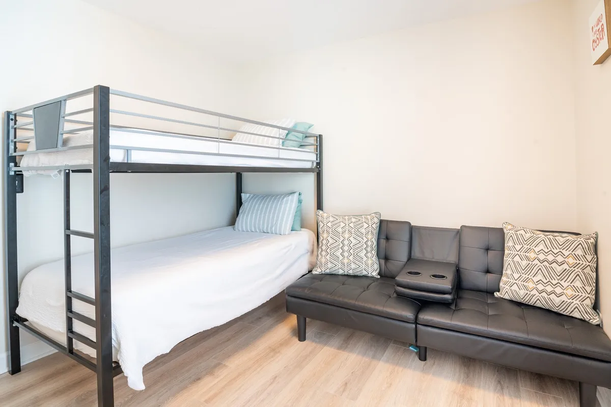 A bunk bed and cozy sofa are the focal points of this casual, family-friendly room. The space is styled for comfort, encouraging conversations, group relaxation, or a fun sleepover atmosphere for kids and cousins.