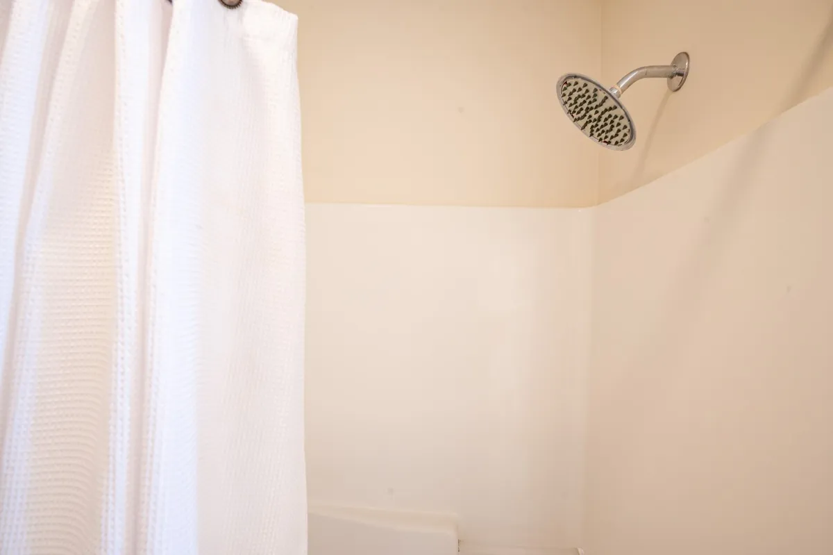 A clean, modern shower with a sleek showerhead and curtain, evoking a sense of calm and refreshment. The space is designed for practical comfort and daily routines.