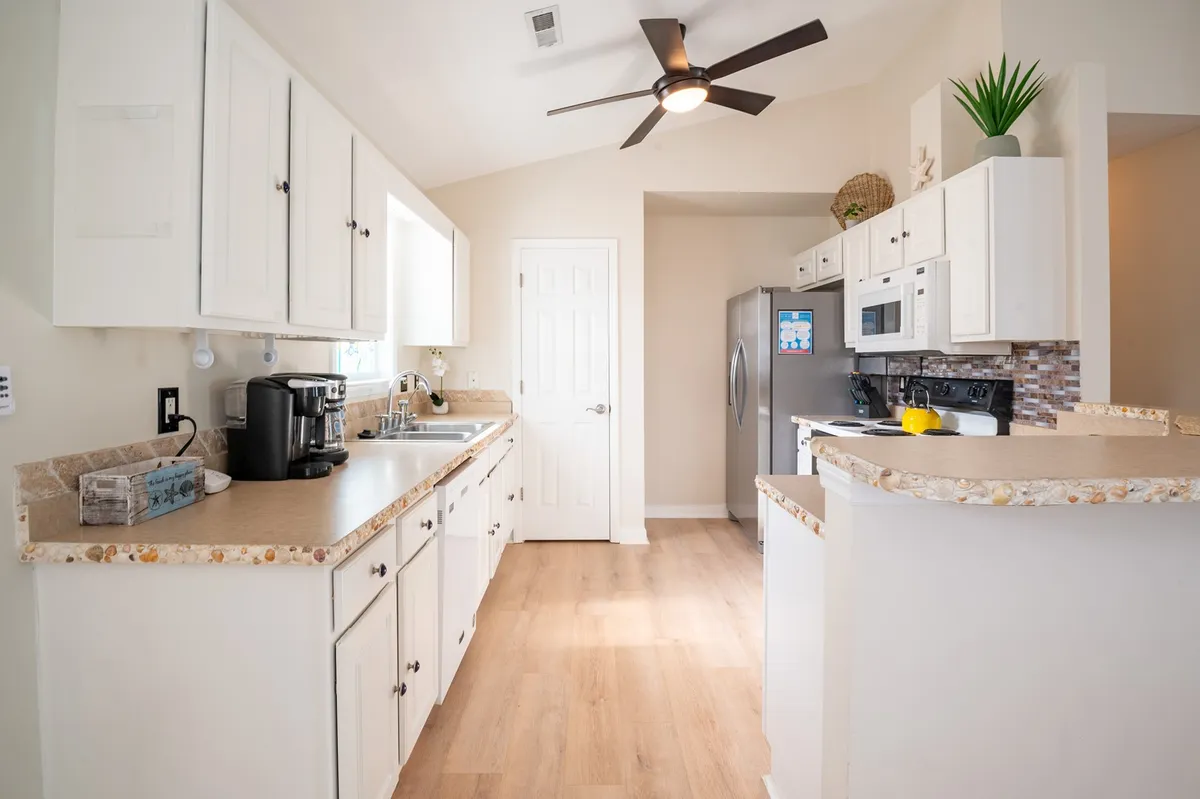 A cozy kitchen scene featuring a central island, stainless steel appliances, a coffee maker, and a decorative plant. The layout encourages conversation and togetherness, with plenty of space for cooking and entertaining.