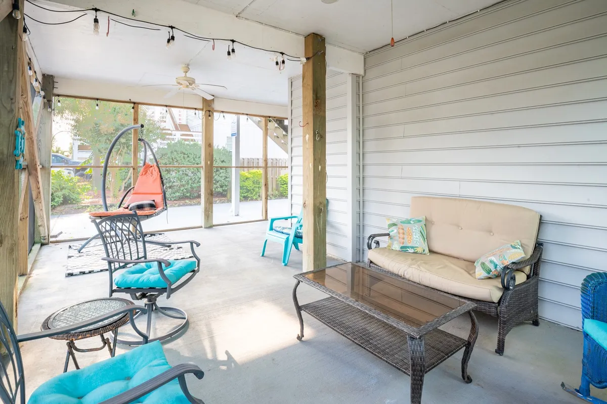 This image showcases a casual, comfortable living area featuring a hanging chair, sofa, and a glass coffee table. Natural light streams into the space, suggesting a connection to the outdoors and an inviting spot for socializing or relaxing with drinks. The arrangement hints at views of the sunset or starlit evenings, reinforcing the idea of shared experiences and easy transitions between relaxation and entertainment.