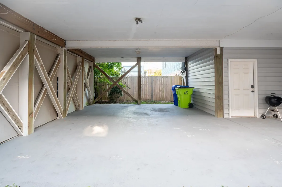 An interior shot beneath the raised home shows the sturdy wooden support beams, a garage door, and practical parking or storage space. The area is functional for parking vehicles and transitioning from outdoor arrival to indoor comfort.